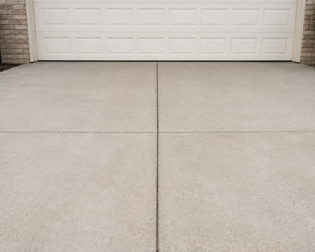 Close-up view of a concrete driveway with joint seams, leading to a garage door.