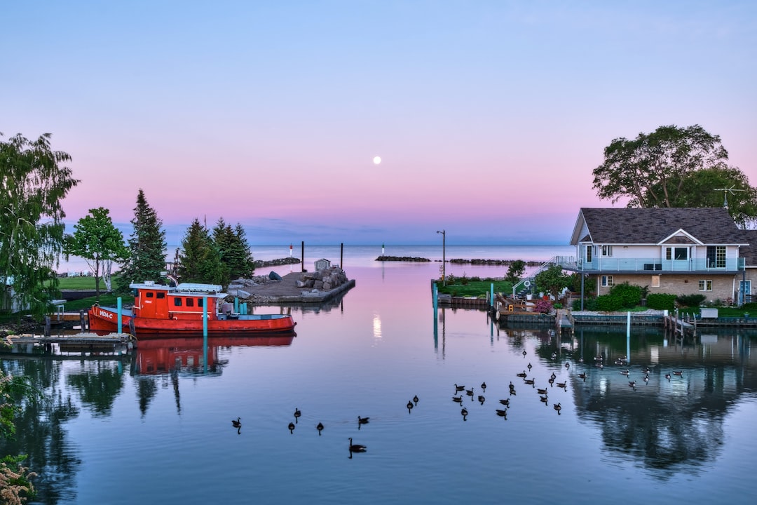 A serene waterfront scene showcasing a quaint house and boats on calm water at dusk.