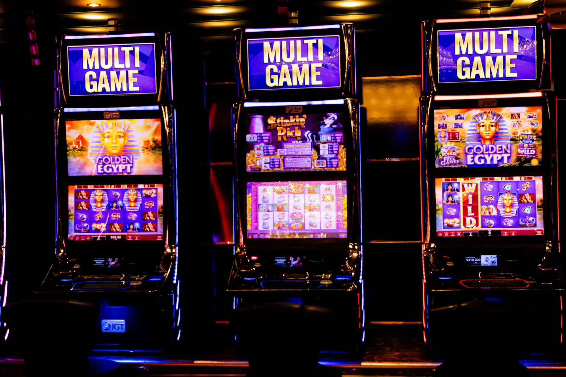 Three illuminated slot machines in a bustling casino at night. — The Evolution of Casino Gaming: From Traditional to Digital