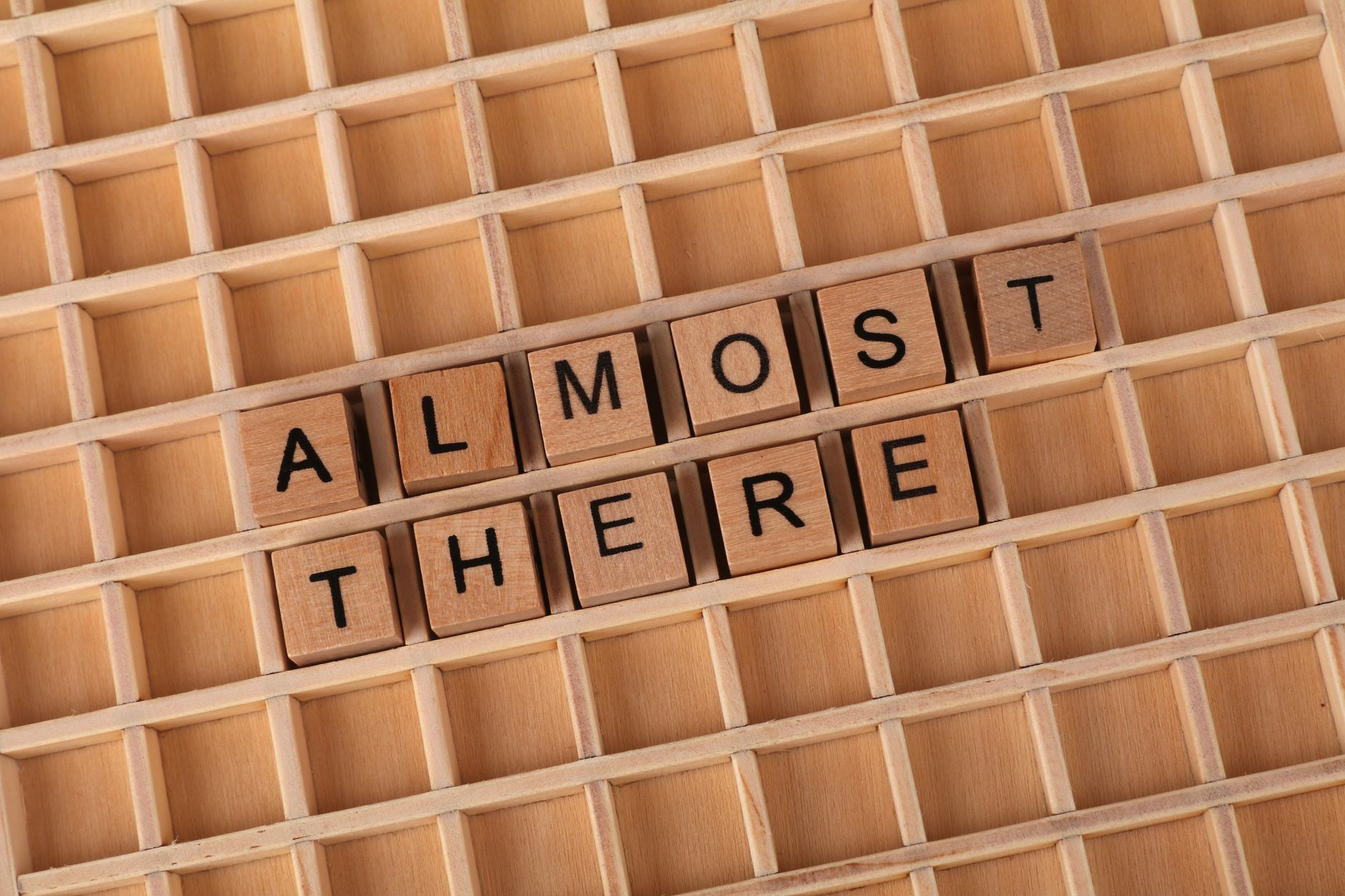 Wooden letter tiles spelling 'Almost There' on a wooden grid, conveying progress and motivation. — The Impact of Artificial I