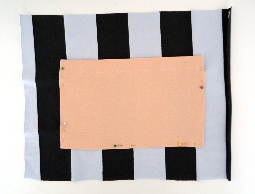 a piece of fabric with colored stripes and a pattern pinned on top